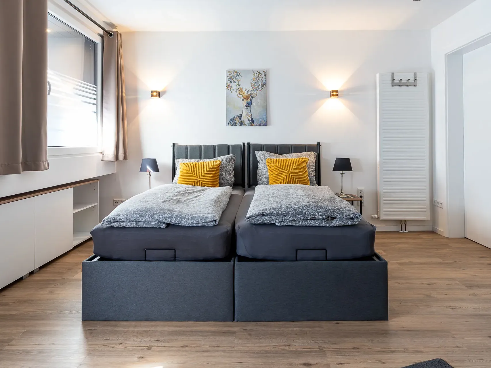 Schlafzimmer in Apartment 1 mit zwei Betten, gelben Kissen und Hirschbild