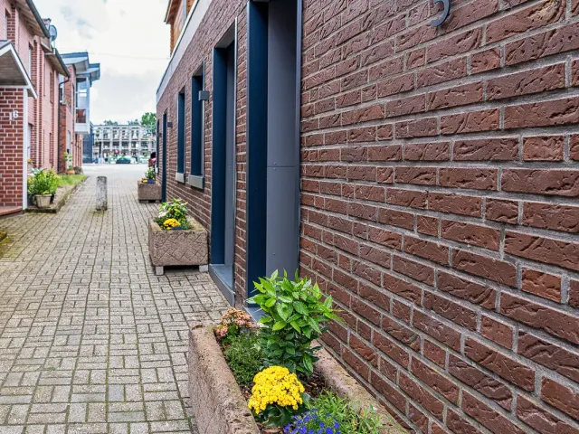Gepflasterter Zugang zu den Apartments mit Blumenkübeln